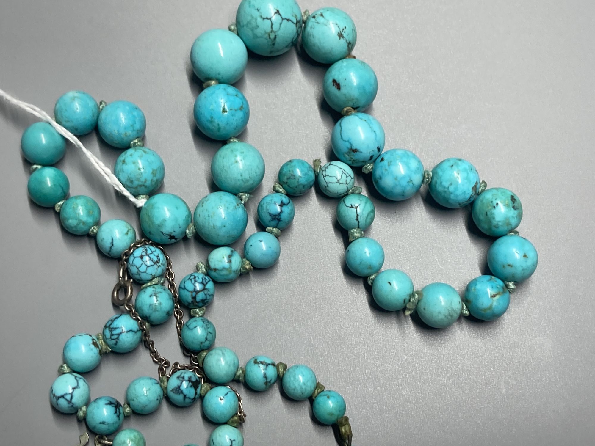 A continental graduated turquoise bead necklace, with marcasite and cultured pearl set white metal clasp, 57cm, gross 73 grams.